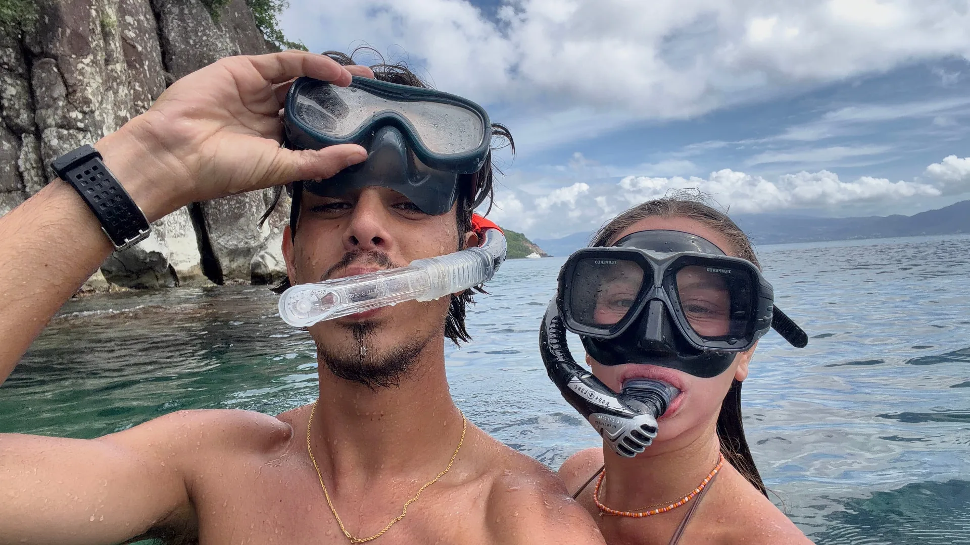 Deux baigneurs équipés de masque et tuba dans une eau turquoise, falaise en arrière-plan