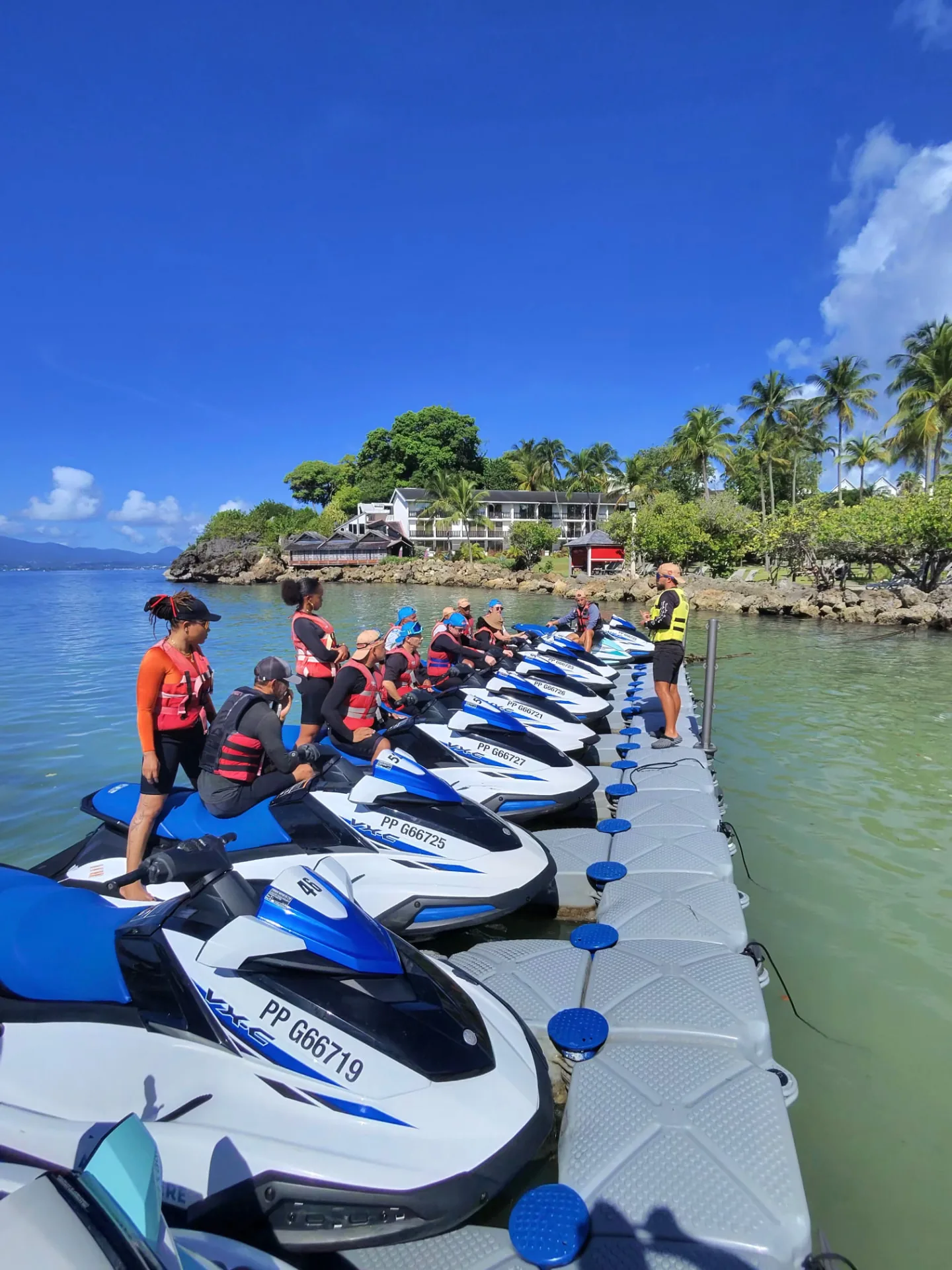 Briefing de sécurité d’un groupe sur un ponton flottant, gilets de sauvetage et jet skis
