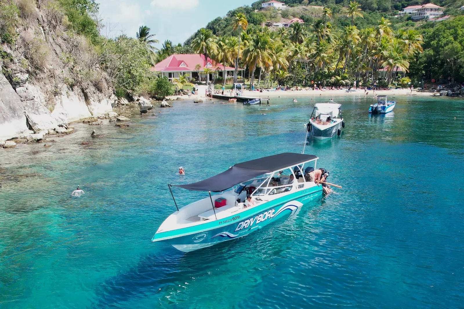 Le Poker Run, l’un des trois speed boats d’Atmosphère, au mouillage dans une anse turquoise des Saintes, devant la plage et les cocotiers